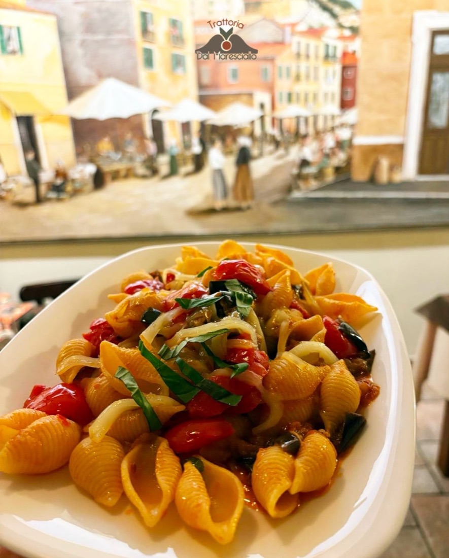 Conchiglioni con melanzane e pomodorini, sullo sfondo il murale della trattoria